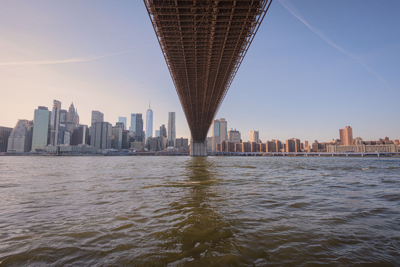 Manhattan skyline viewed from the water under a bridge